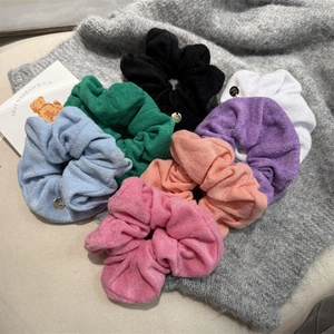Set of colorful towel fabric hair scrunchies with gold charm on grey background