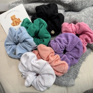 Colorful towel fabric scrunchies set with metal tags on a cozy fabric background
