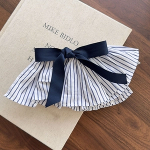 Elegant blue and white striped pleated bow hair clip on a vintage book surface