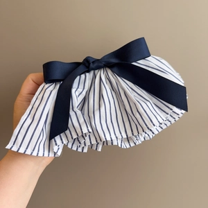 Detail of blue striped pleated spring hair clip with large navy satin bow decoration