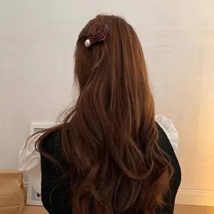 Brown rose hair clip with pearl accent worn on wavy hair in a lifestyle setting