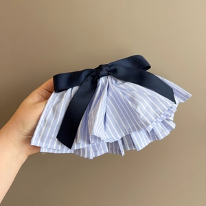 Detailed view of blue striped pleated hair clip with navy satin bow accessory
