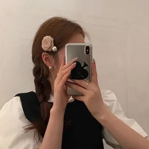 Elegant beige fabric rose hair clip with pearl detail and matching accessories on a model