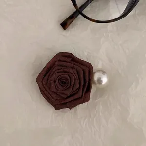 Detail of dark rose hair clip with fabric petals and a large faux pearl decoration