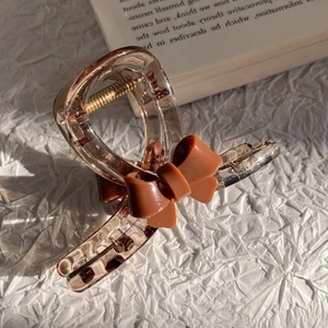 Elegant translucent brown hair claw clip with a dark brown ribbon bow on white fabric