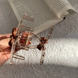 Detailed macro view of an amber acrylic bow hair claw clip held over a vintage book