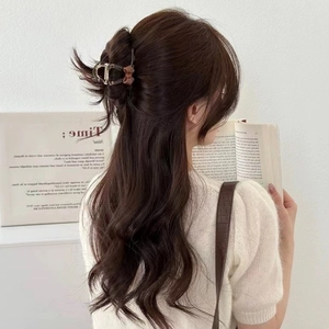 Detail view of a brown acrylic bow hair claw clip for elegant hairstyle styling