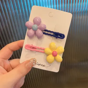Close-up of colorful floral hair clips for girls on a white card against a blue background
