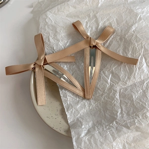 Dettaglio di fermagli per capelli con fiocco in raso champagne su un vassoio decorativo