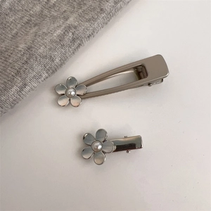 Détails de barrettes argentées avec motifs floraux et perles fantaisie élégantes