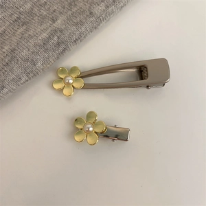 Détail de pinces à cheveux dorées ornées de fleurs élégantes et perles blanches