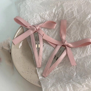 Dettaglio di fermagli per capelli con fiocco in nastro rosa su piatto in ceramica