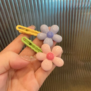 Close-up of cute floral resin hair clips in vibrant purple and pink for young girls