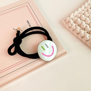 Nahaufnahme eines schwarzen elastischen Haargummis mit buntem Smiley-Anhänger