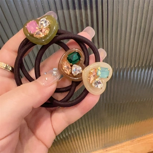 Close-up of three elastic hair ties with heart-shaped resin charms and colorful rhinestones