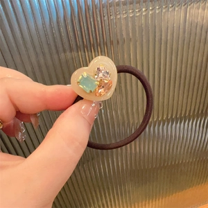 Macro detail of sweet heart rhinestone hair tie with mint green and orange crystal stones
