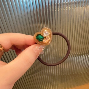 Detail of amber heart resin charm with colorful rhinestones on a brown elastic hair tie