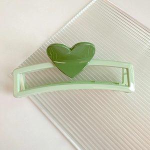 Détail d'une pince à cheveux rectangulaire verte de 13cm avec décor de cœur