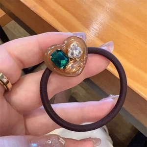 Jelly heart hair tie with three colorful inlaid gemstones on a brown resin base