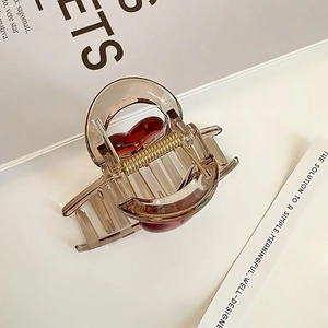 Gros plan sur une pince à cheveux en acrylique marron avec un cœur rouge élégant