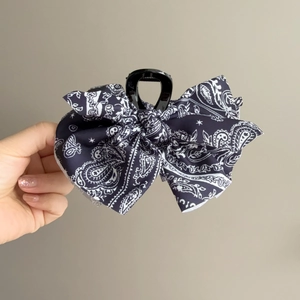 Détail d'une pince à cheveux vintage à motif paisley noir avec un nœud élégant
