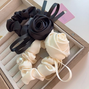 Détail de chouchous rose en satin avec longs rubans et breloque perle dans une boîte bois
