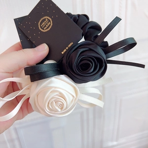 Détail d'un chouchou en satin fait main avec roses noires et blanches et étiquette