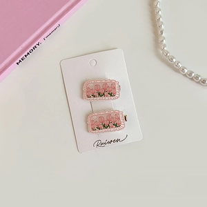 Détail de barrettes à motif de tulipes roses sur carte avec perles et décor doux