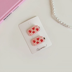 Détail de barrettes à cheveux à carreaux rouges et fleurs avec bords ondulés sur carte