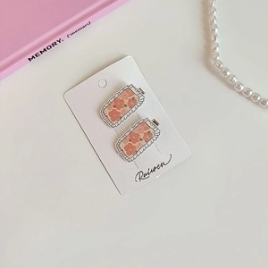 Lot de 2 barrettes carrées à fleurs avec bords ondulés sur carte de présentation