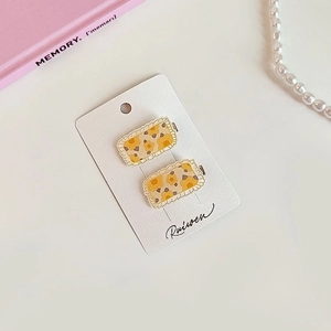 Détail de deux barrettes à fleurs jaunes avec bordure en dentelle blanche
