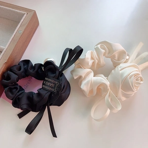 Détail de chouchous en satin avec roses élégantes en tissu et perles en noir et blanc