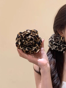 Detail shot of large leopard print flower hair clip showing texture and fabric petals