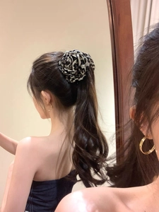 Detailed view of a large leopard print flower hair claw clip worn on a high ponytail