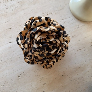 Detailed top view of a large leopard print fabric flower hair claw with satin texture