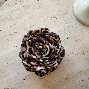 Detailed macro view of large leopard print fabric flower hair claw with tiered petals