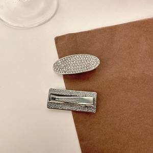 Close-up of silver hair clip set with rhinestone inlay and textured metallic duckbill clip