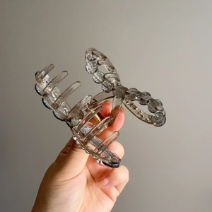 Detail of grey bow hair claw clip with silver sequins and golden metal spring mechanism