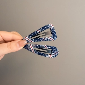 Detail showing blue plaid fabric texture on triangular and oval metal hair clips