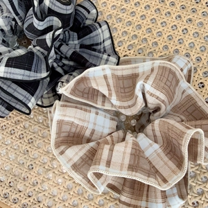 Lot de chouchous à motif écossais classique noir et beige posés sur un tapis tissé