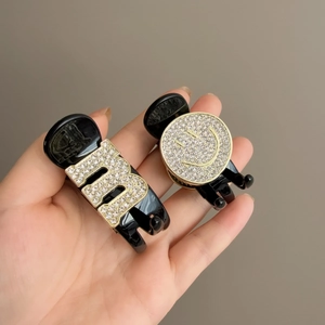 Detail of mini black hair clips with sparkling rhinestone B letter and smiley face motifs