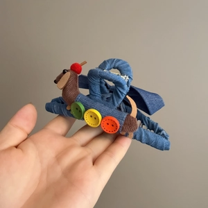 Dettaglio della pinza per capelli in denim blu con bassotto di peluche e bottoni colorati