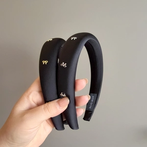 Serre-tête rembourré noir élégant avec petits nœuds métalliques en or et en argent