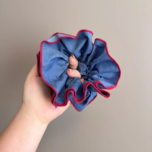 Détail d'un chouchou en denim bleu avec coutures rouges contrastées et texture