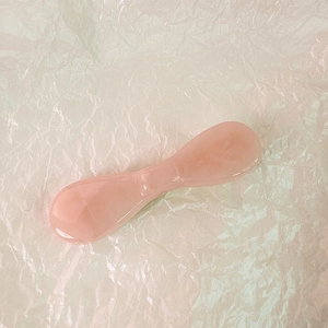 Vue détaillée d'un outil de massage facial en quartz rose poli en forme de nœud