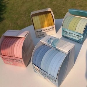 Set of four pastel macaron gradient hair bands in neat boxes on white surface