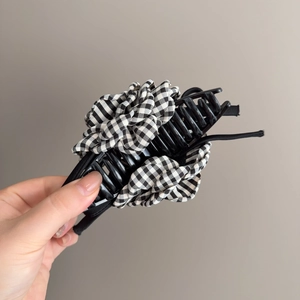 Grande pince à cheveux à fleurs à carreaux noirs et blancs tenue en main pour la taille