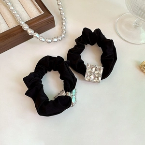 Detail view of black silk scrunchies featuring luxury square crystal rhinestones