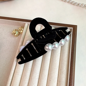 Grande pince à cheveux noire floquée élégante avec perles sur un plateau de bijoux