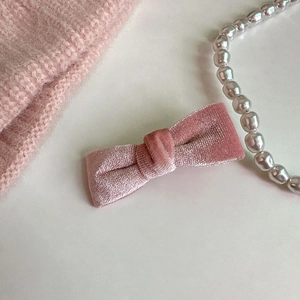 Détail d'une barrette à cheveux en velours rose poudré avec collier de perles élégant
